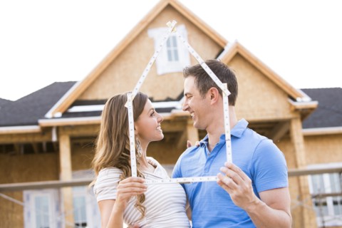 Caucasian couple holding frame near house under construction