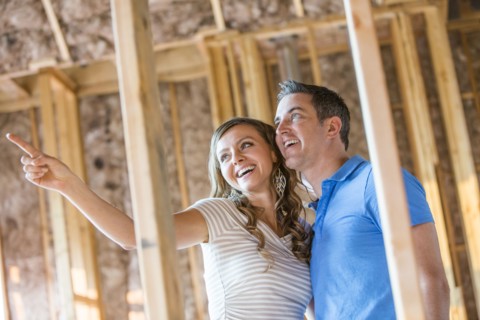 Caucasian couple admiring house under construction