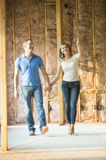 Caucasian couple walking in house under construction