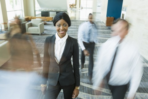 Businesswoman standing still in busy office lobby