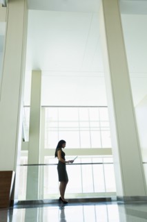 Hispanic businesswoman using digital tablet in office hallway