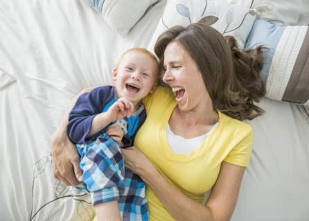 Caucasian mother and son playing on bed