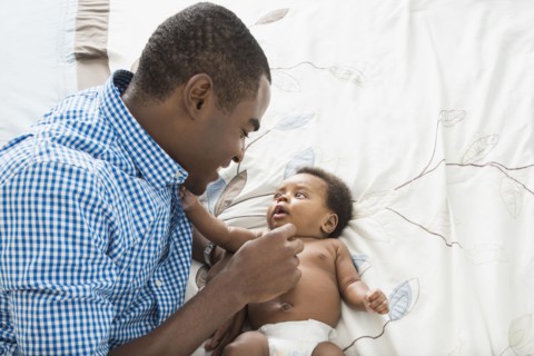 Father and baby son laying on bed