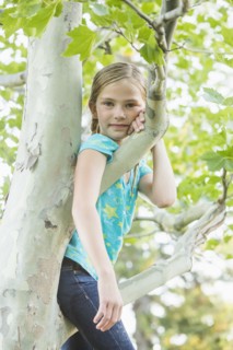 Smiling Caucasian girl climbing tree outdoors