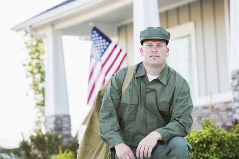 Caucasian soldier kneeling near house