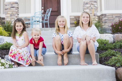 Caucasian sisters smiling on front stoop