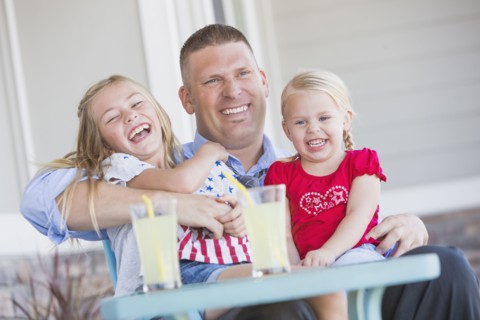 Caucasian father and daughters laughing on porch