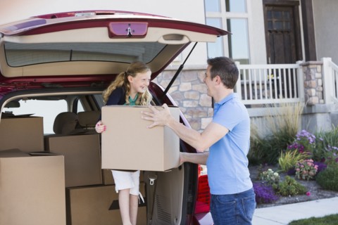 Caucasian family unpacking cardboard boxes from car