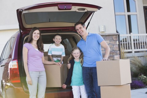 Caucasian family unpacking cardboard boxes from car