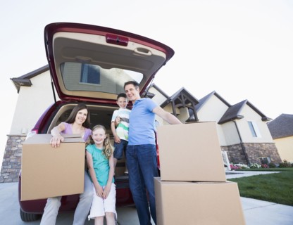 Caucasian family unpacking cardboard boxes from car