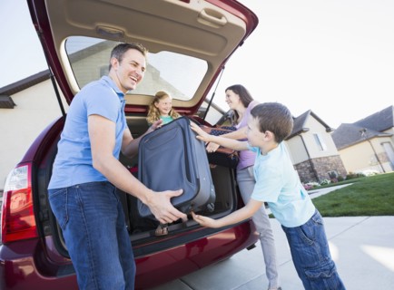 Caucasian family unpacking suitcases from car
