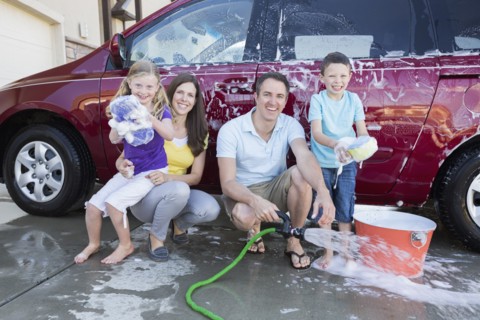 Caucasian family washing car in driveway