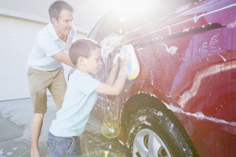 Caucasian father and son washing car in driveway
