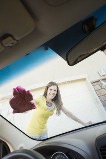 Caucasian woman washing car windshield
