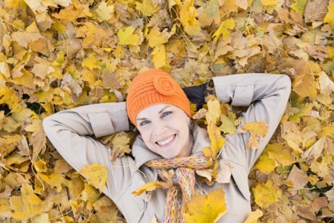Older Caucasian woman smiling in autumn leaves