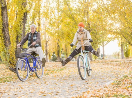 Older Caucasian couple riding bicycles on autumn leaves