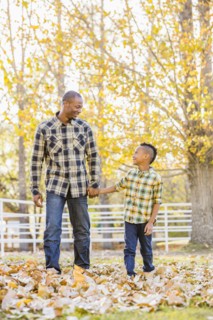 Father and son holding hands in autumn leaves
