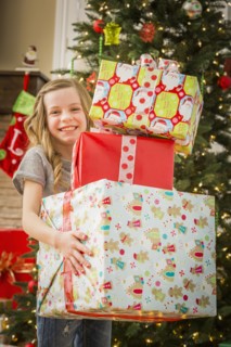Caucasian girl holding pile of Christmas gifts