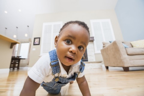 Black baby crawling on living room floor