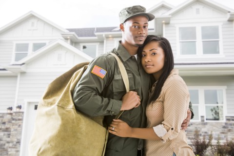 Returning soldier and wife standing outside house