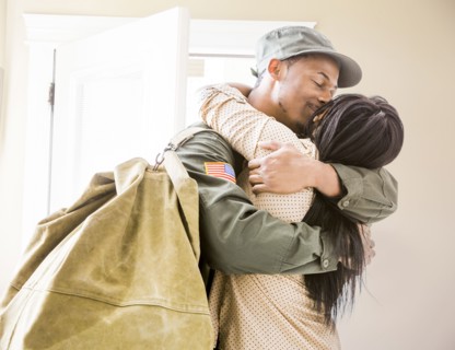 Returning soldier kissing wife in hallway