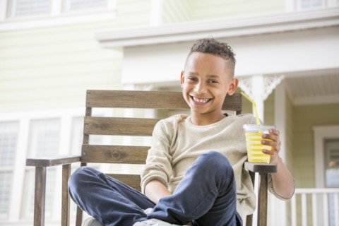 Black boy drinking orange juice in backyard