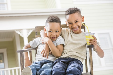 Brothers hugging in armchair in backyard