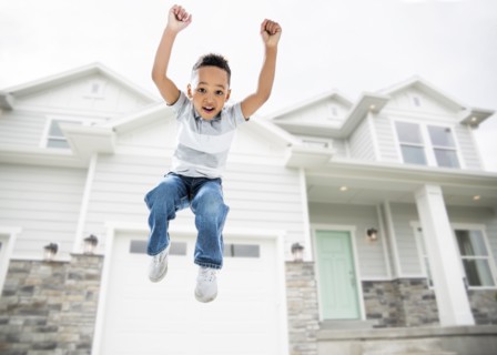Mixed race boy jumping for joy in driveway