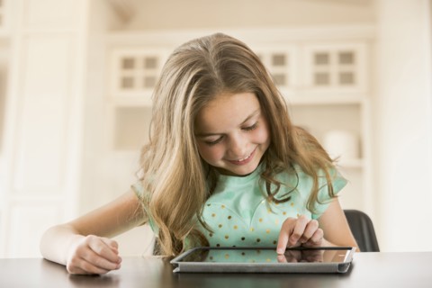 Caucasian girl using digital tablet at table