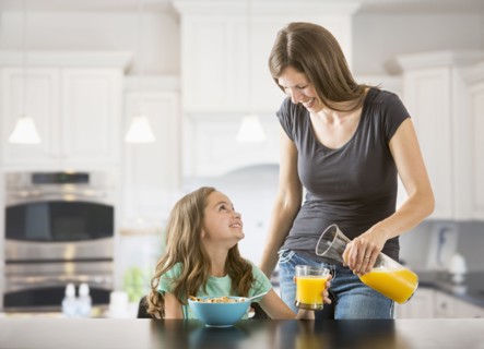 Caucasian mother pouring juice for daughter in kitchen