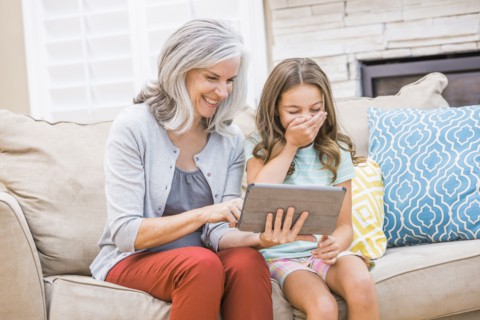Caucasian grandmother and granddaughter using digital tablet on sofa