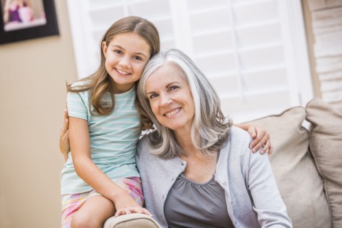 Caucasian grandmother and granddaughter hugging on sofa