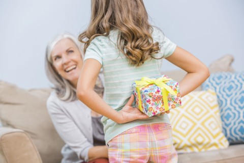 Caucasian girl hiding gift for grandmother behind back