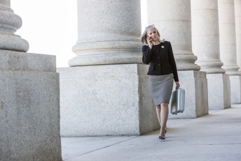Caucasian businesswoman talking on cell phone under columns