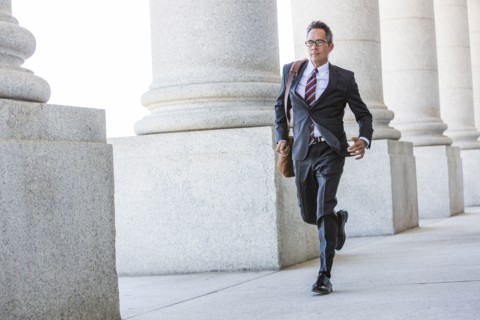 Mixed race businessman walking under columns