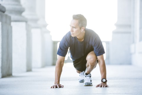 Mixed race man stretching outside courthouse