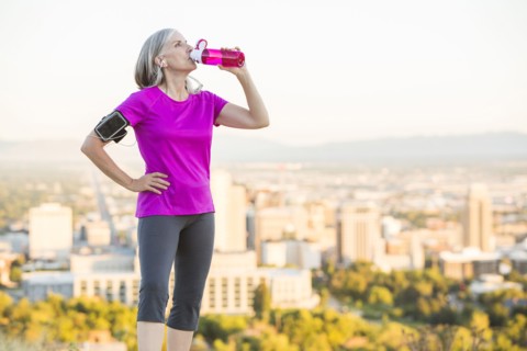 Caucasian woman drinking water bottle on urban hilltop