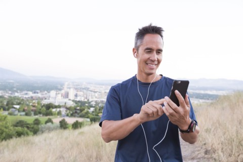 Mixed race man using cell phone on hilltop