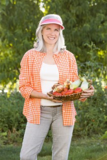 Caucasian woman holding basket of vegetables in garden
