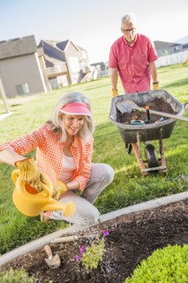 Caucasian couple gardening in backyard