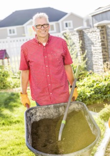 Caucasian man pushing wheelbarrow of dirt