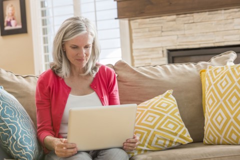 Caucasian woman using laptop on sofa
