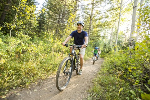 Caucasian father and children riding mountain bikes