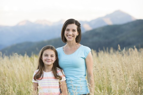 Caucasian mother and daughter smiling in field