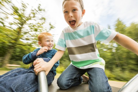Caucasian boys playing on merry-go-round