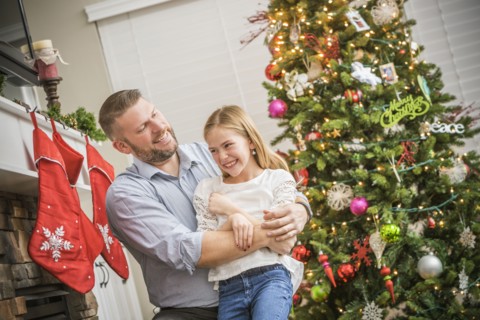 Caucasian father and daughter hugging near Christmas tree