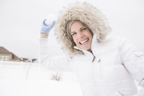 Caucasian woman throwing snowball in snow