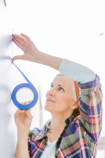 Caucasian woman taping off painting area