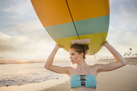 Caucasian woman carrying surfboard on beach