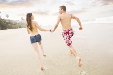 Caucasian couple running on beach